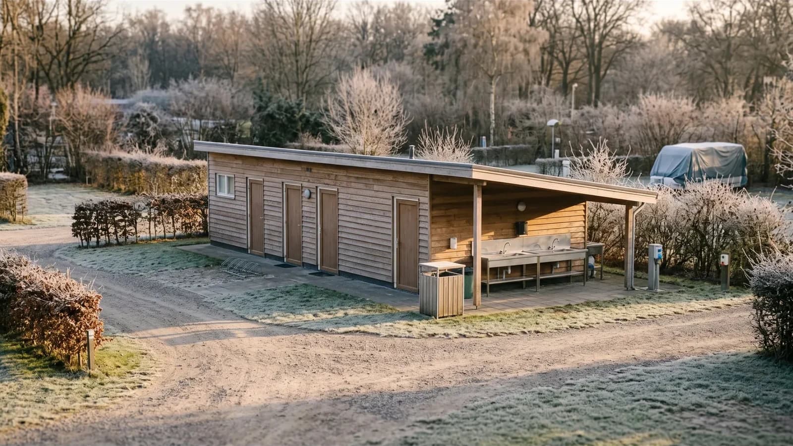 Gesloten sanitairgebouw op een camping in de winter, met rijp op het gras